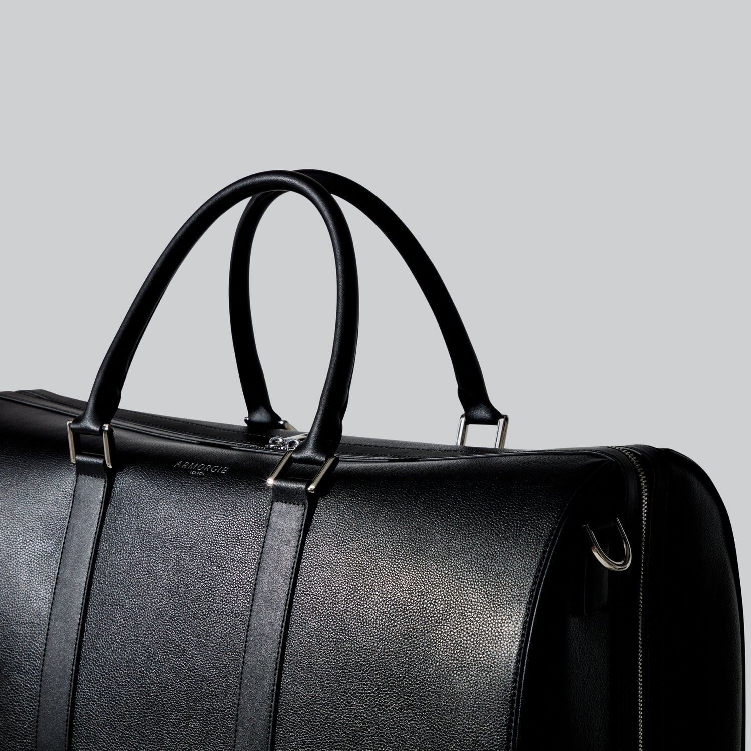 An image of a large holdall made of black pebble leather with smooth leather trims and silver hardware