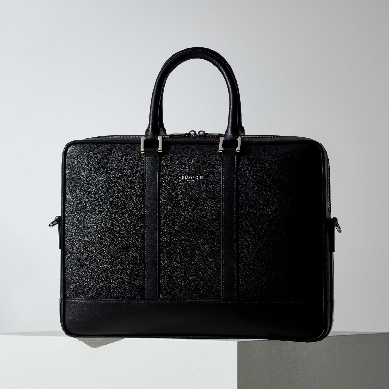 An image of a soft but structured briefcase made from pebbled leather with smooth leather trims and silver hardware